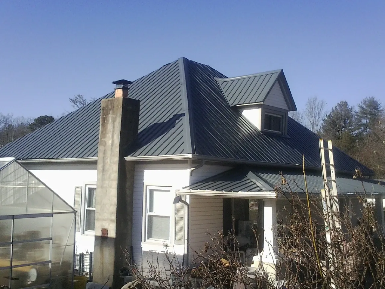 Dark blue standing seam metal roof on a white farmhouse with dormer — Slate & Tile Roof Repair by Roofing Brothers in Stockton