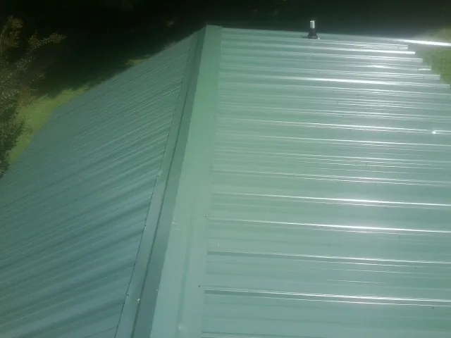 New green metal panels meeting at the ridge of a roof — Flat Roof Repair work by our crew in Stockton